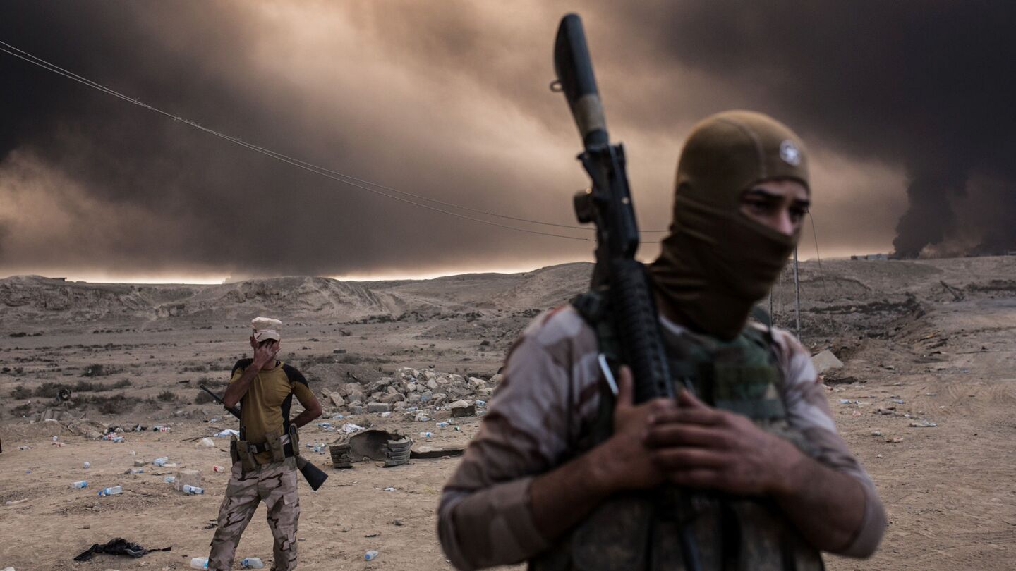 Iraqi soldiers look on as smoke rises from the Qayyarah area south of Mosul on Oct. 19, 2016, as Iraqi forces take part in an operation against Islamic State to retake Mosul.