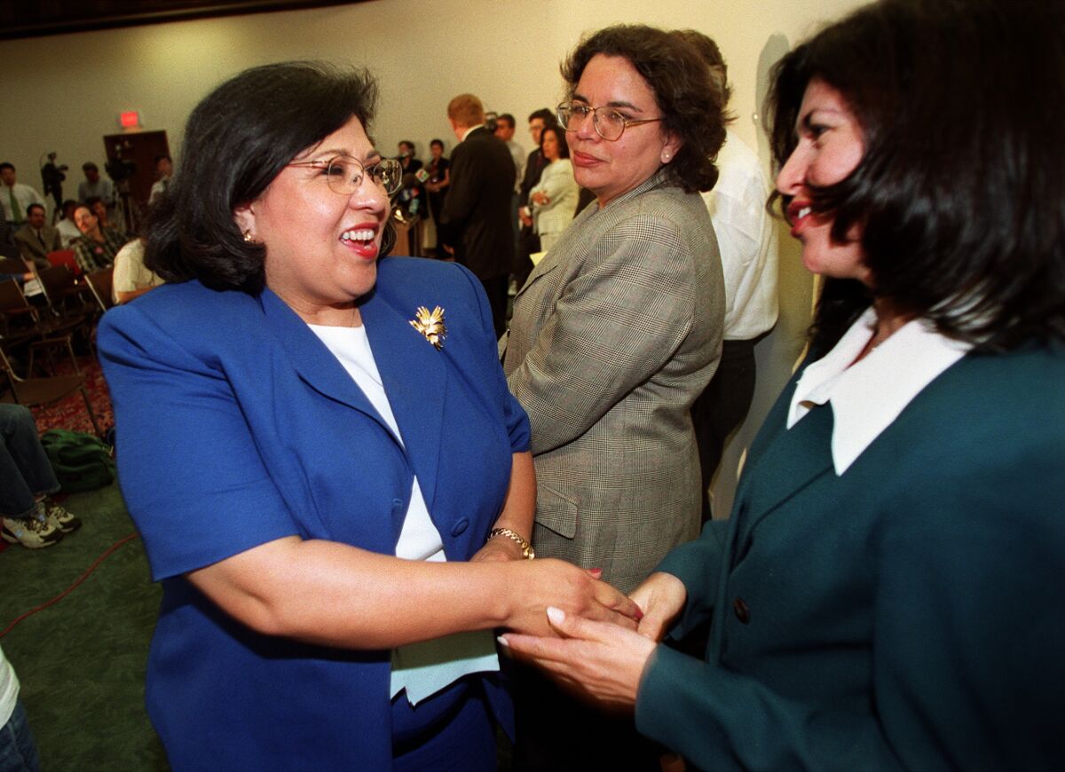 Gloria Molina shakes hands with another woman.