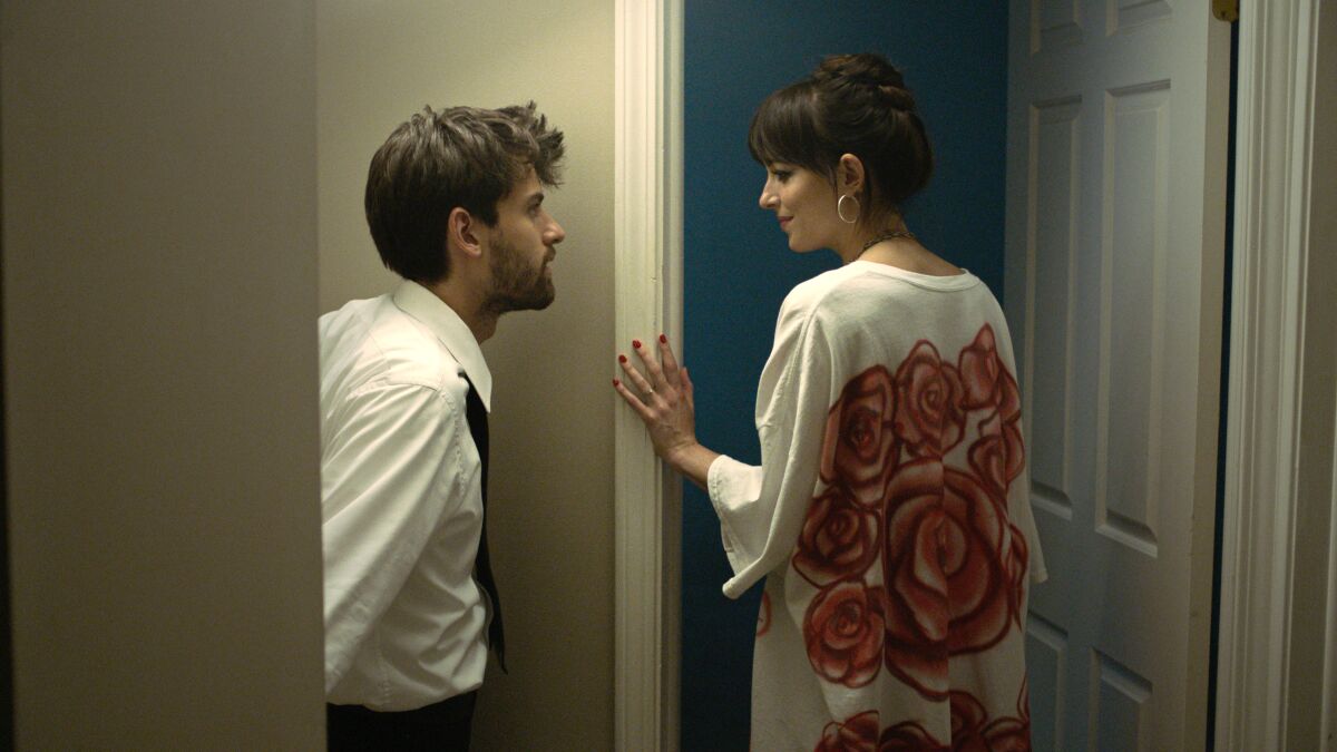 A man and a woman talk outside a door