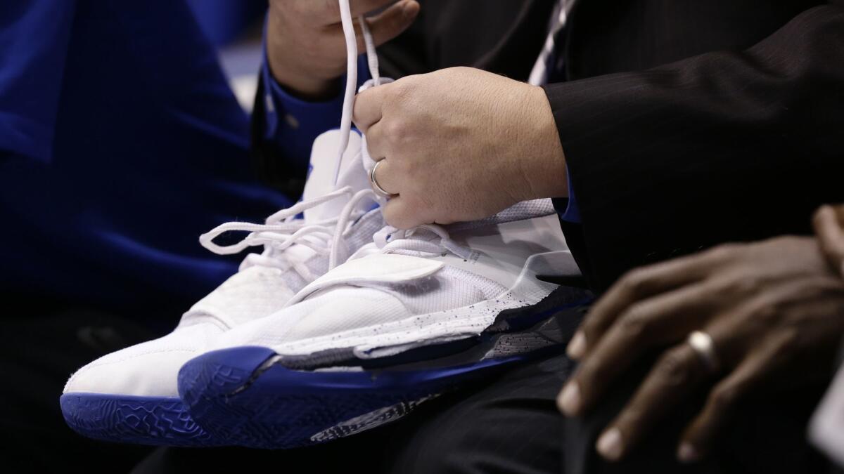 A trainer holds Duke's Zion Williamson's shoes after Williamson left the game against North Carolina due to an injury.