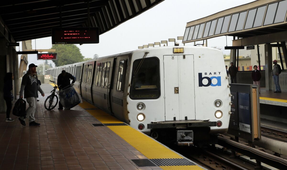 Bay Area Rapid Transit travelers wait to board an arriving train in Oakland. A strike might shut down the system early Tuesday.