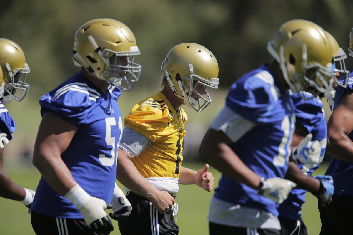 UCLA quarterback Jerry Neuheisel, middle, runs off the field with offensive linemen during the first day of camp at Cal State San Bernardino on Aug. 10.