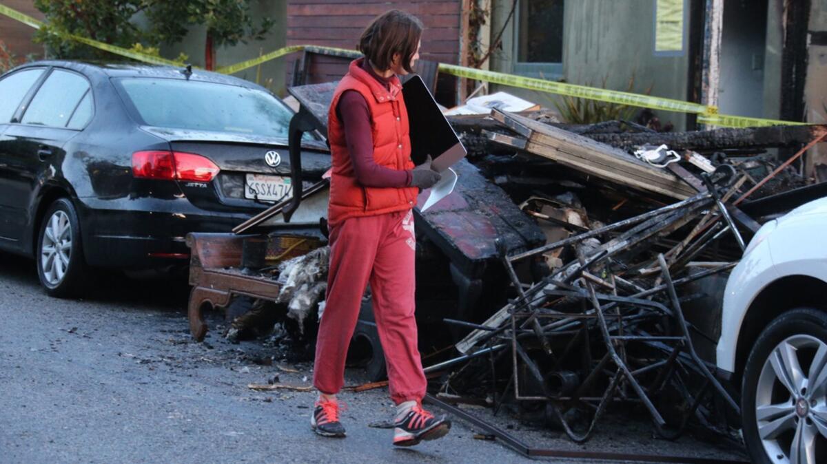 A family member salvages a computer from a home in Pacific Palisades, where five people were injured and a family pet was killed when flames swept through two homes early Thursday.