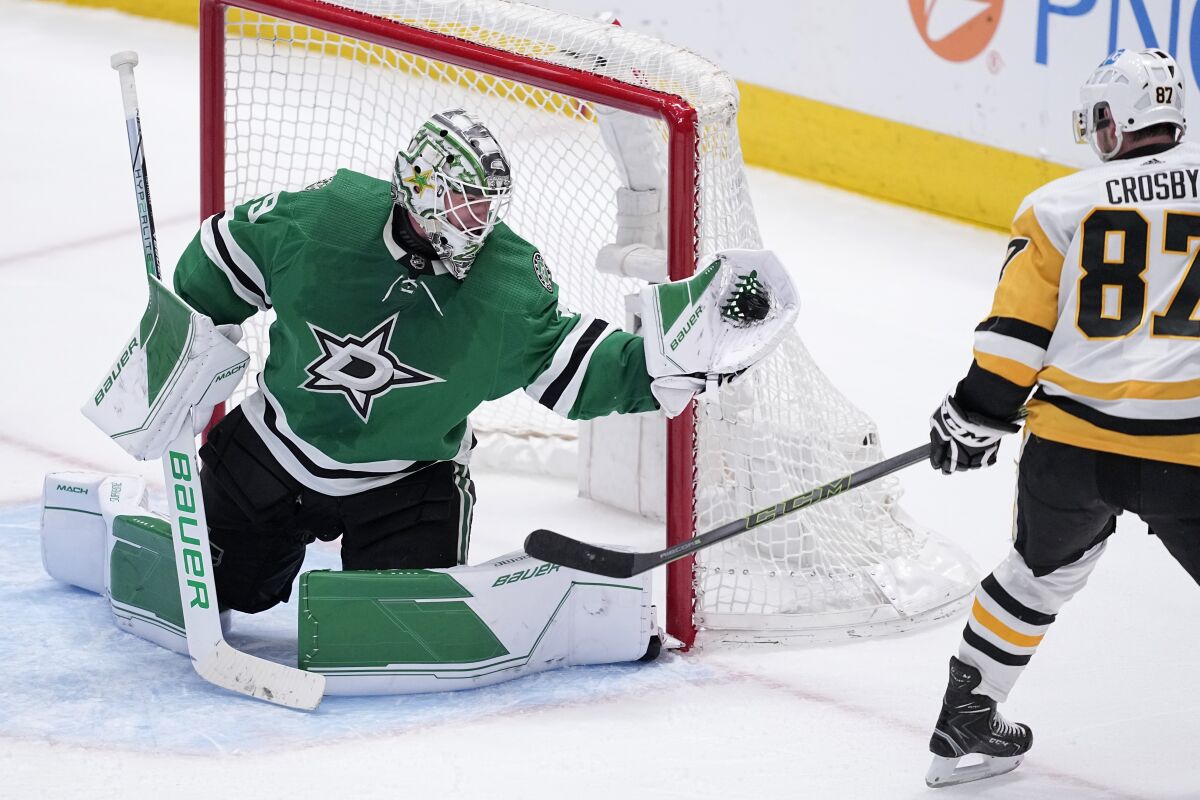 Dallas Stars goaltender Jake Oettinger (29) gloves a shot from Pittsburgh Penguins center Sidney Crosby (87) late in the third period of an NHL hockey game, Thursday, March 23, 2023, in Dallas. (AP Photo/Tony Gutierrez)