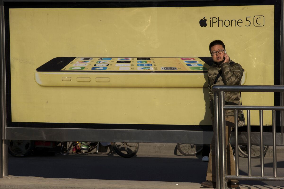 A Chinese man uses his mobile phone near an advertisement for Apple's iPhone 5C on a street in Beijing on Monday.