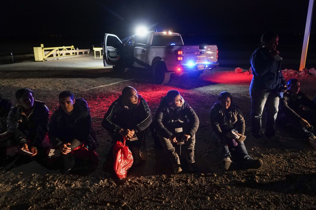 Varios migrantes esperan ser procesados por las autoridades estadounidenses luego de cruzar la frontera