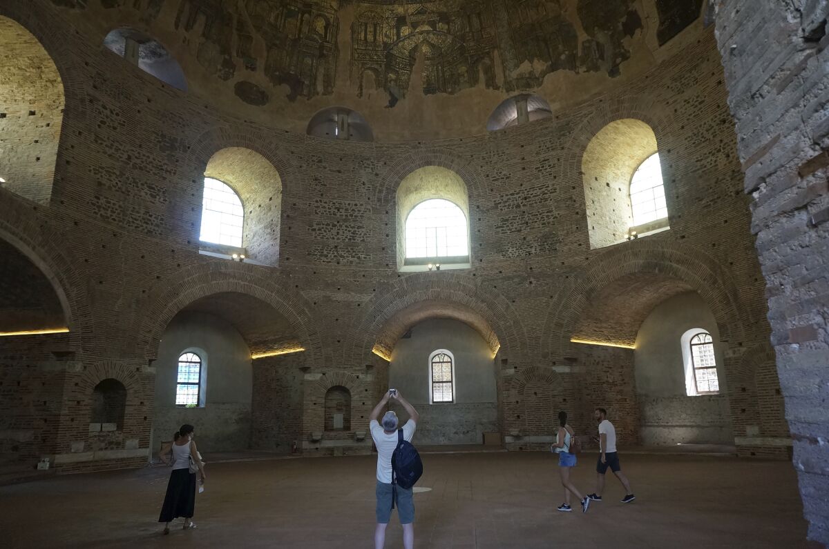 Visitors admire the Byzantine mosaics adorning the gigantic dome of the Rotunda on Saturday, June 25, 2022, in Thessaloniki, Greece. The circular building was built as a Roman temple or mausoleum in the 300s, shortly after became a Christian church, later on a mosque – and is now a museum, though liturgy is still celebrated a few times a year. (AP Photo/Giovanna Dell'Orto)