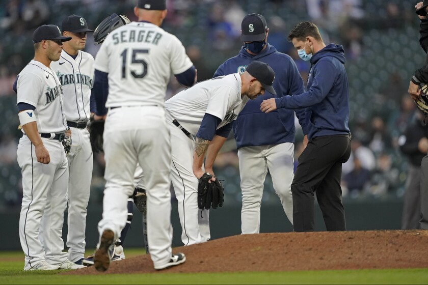 Seattle Mariners starting pitcher James Paxton, third from right, talks with manger Scott Servais, second from right, and a trainer after he experienced an injury, during the second inning of the team's baseball game against the Chicago White Sox on Tuesday, April 6, 2021, in Seattle. Paxton left the game. (AP Photo/Ted S. Warren)