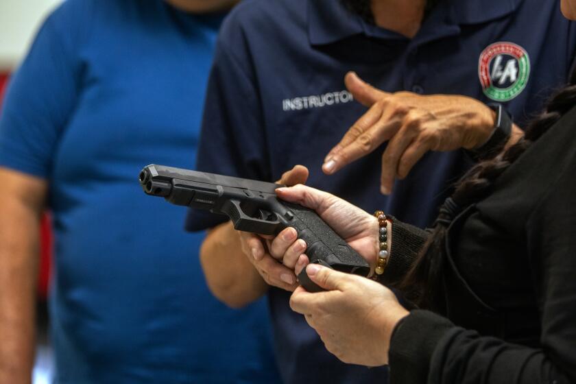 Norwalk, CA - October 29, 2023: Instructor Tom Nguyen, middle, founder of L.A. Progressive Shooters instructs Nikki Shrieves, 41, right, during a firearms education course in Norwalk, CA October 29, 2023. Nikki is holding a 9mm Glock. (Francine Orr/ Los Angeles Times)