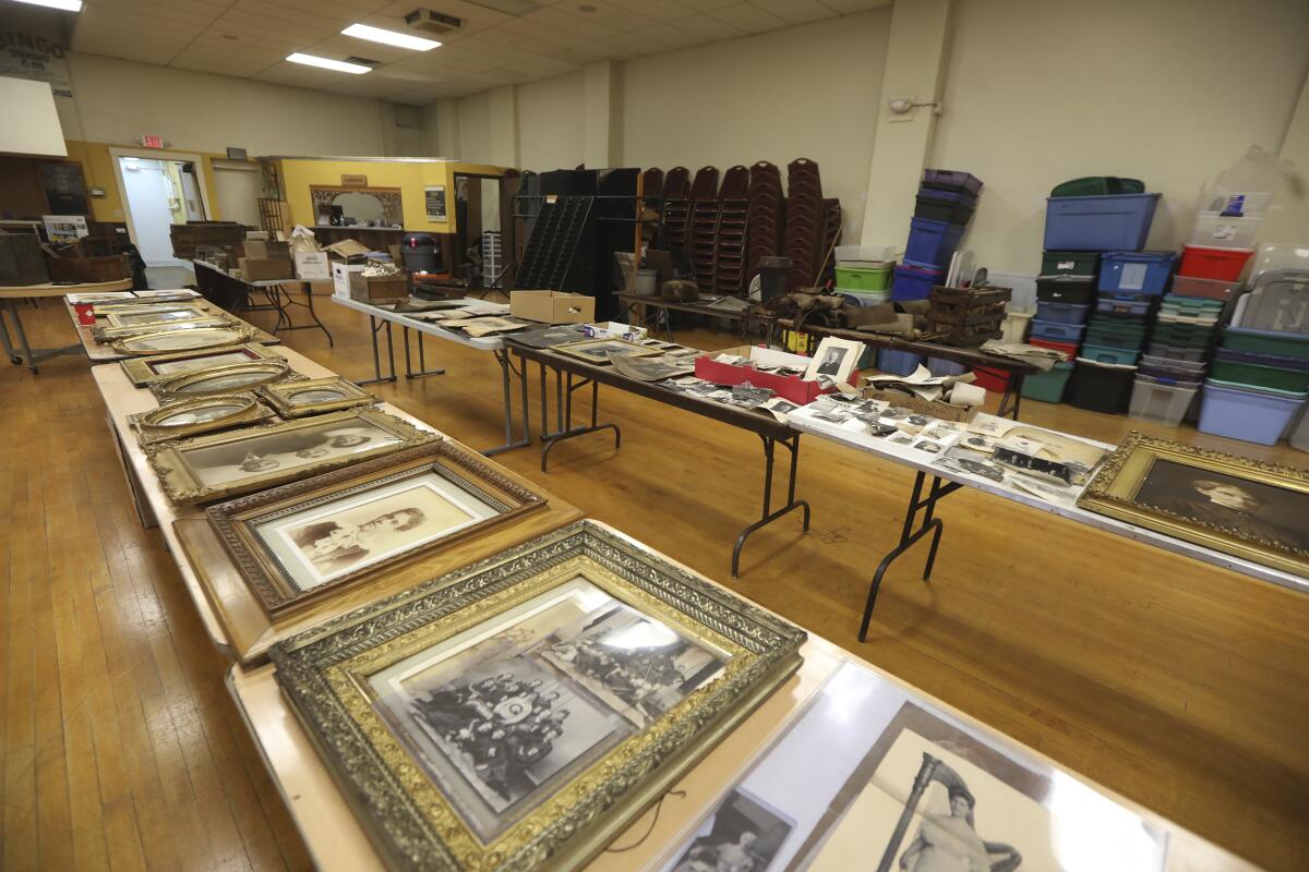 In this Jan. 12, 2021 photo, tables are filled with prints of all sizes that were found in an attic and brought to the antique and auction shop in Canandaigua, N.Y. A rare framed photograph of Susan B. Anthony is being auctioned with a starting price of $5,000. The 20-by-16-inch photo was found in an concealed attic space in a building in Geneva, N.Y, after the property was sold in December. The owner of the building, David Whitcomb, has worked with an antiques dealer to bring some 350 items discovered in the attic to auction. (Tina MacIntyre-Yee/Democrat & Chronicle via AP)