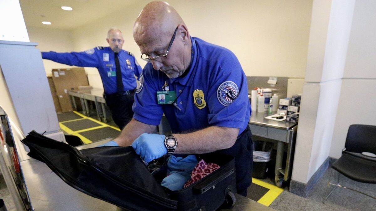 In this Nov. 21, 2014 photo, a Transportation Security Administration agent checks a bag at a security checkpoint area at Midway International Airport in Chicago. To reduce turnover, the TSA has proposed a new training program, but the union for screeners is not impressed.