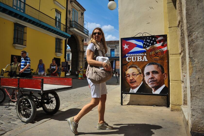 A tourist walks next to a poster of Cuban president Raul Castro and U.S. President Barack Obama on March 17, 2016. Hundreds of workers have been scrambling for days to touch up building facades, patch potholes and spiff up Havana's monuments ahead of Obama's visit.