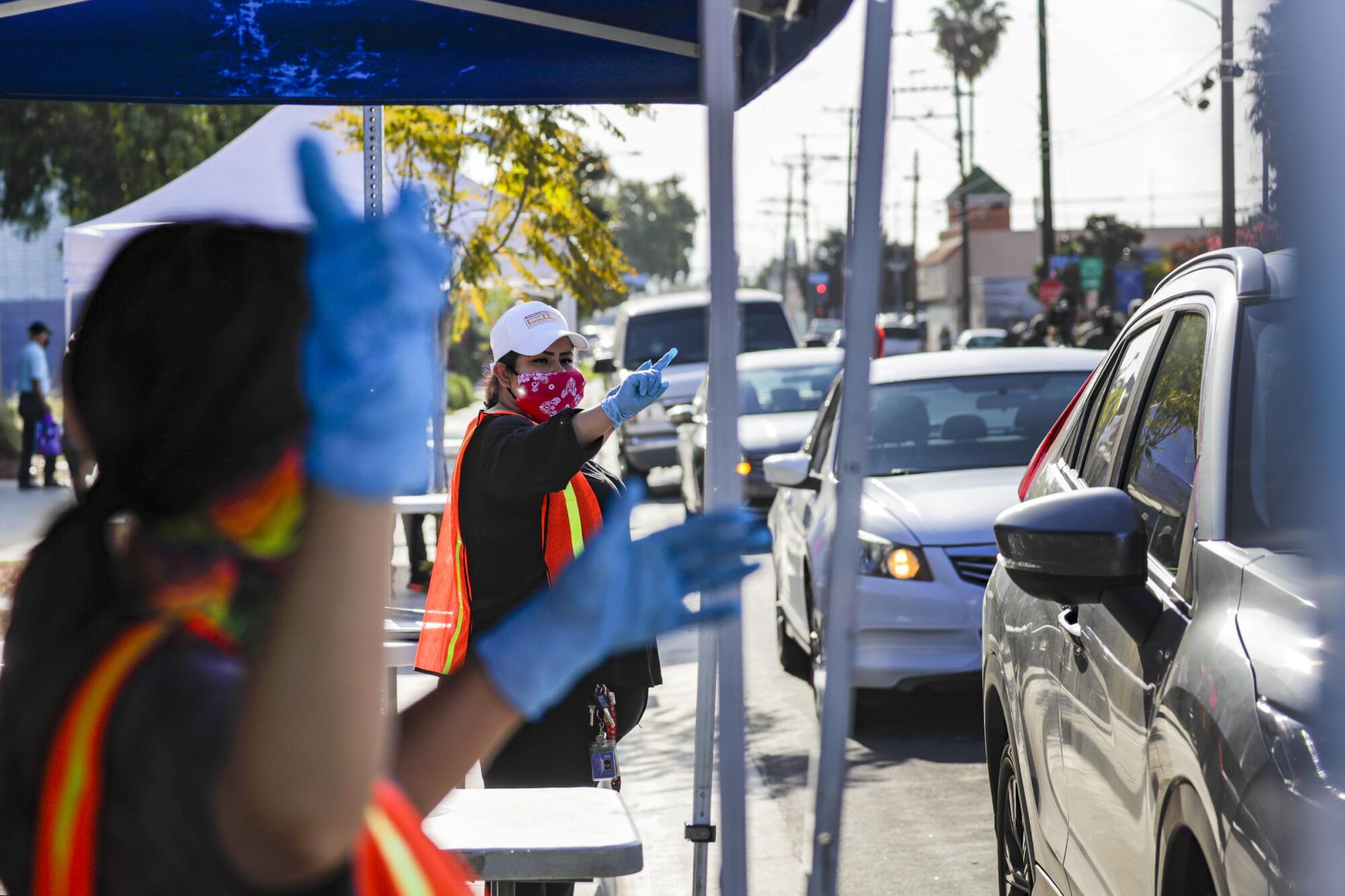 LAUSD cafeteria crew directs cars approaching meal bag distribution stations