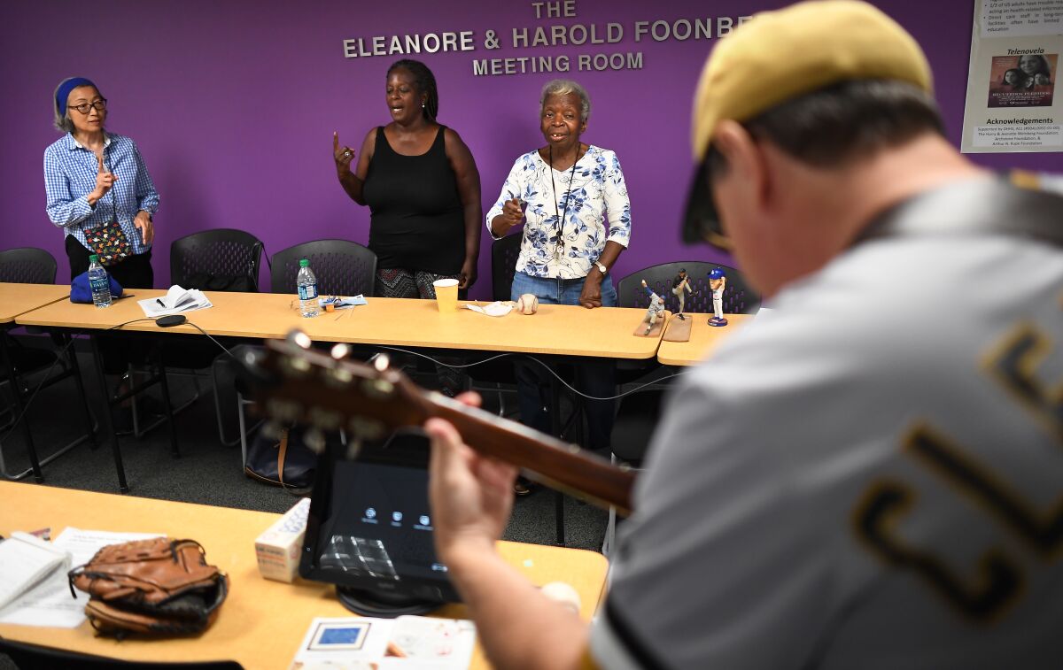 Jon Leonoudakis plays guitar as Dolores Jones, right, sings along with daughter Freda Cain and researcher Kimi Ego during a July 27 meeting in Los Angeles held by BasebALZ, a group that uses baseball to help stir the memories of patients with dementia.