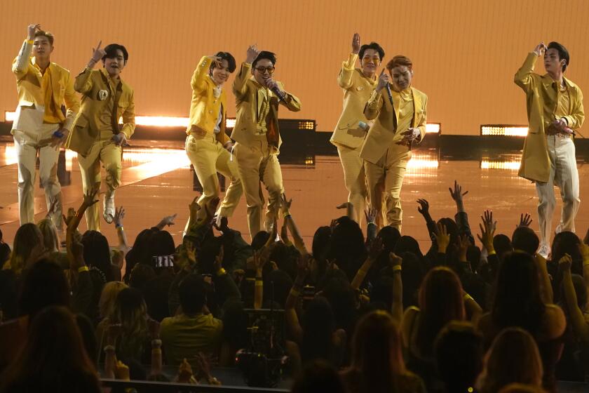 Seven men dancing on a stage in yellow suits