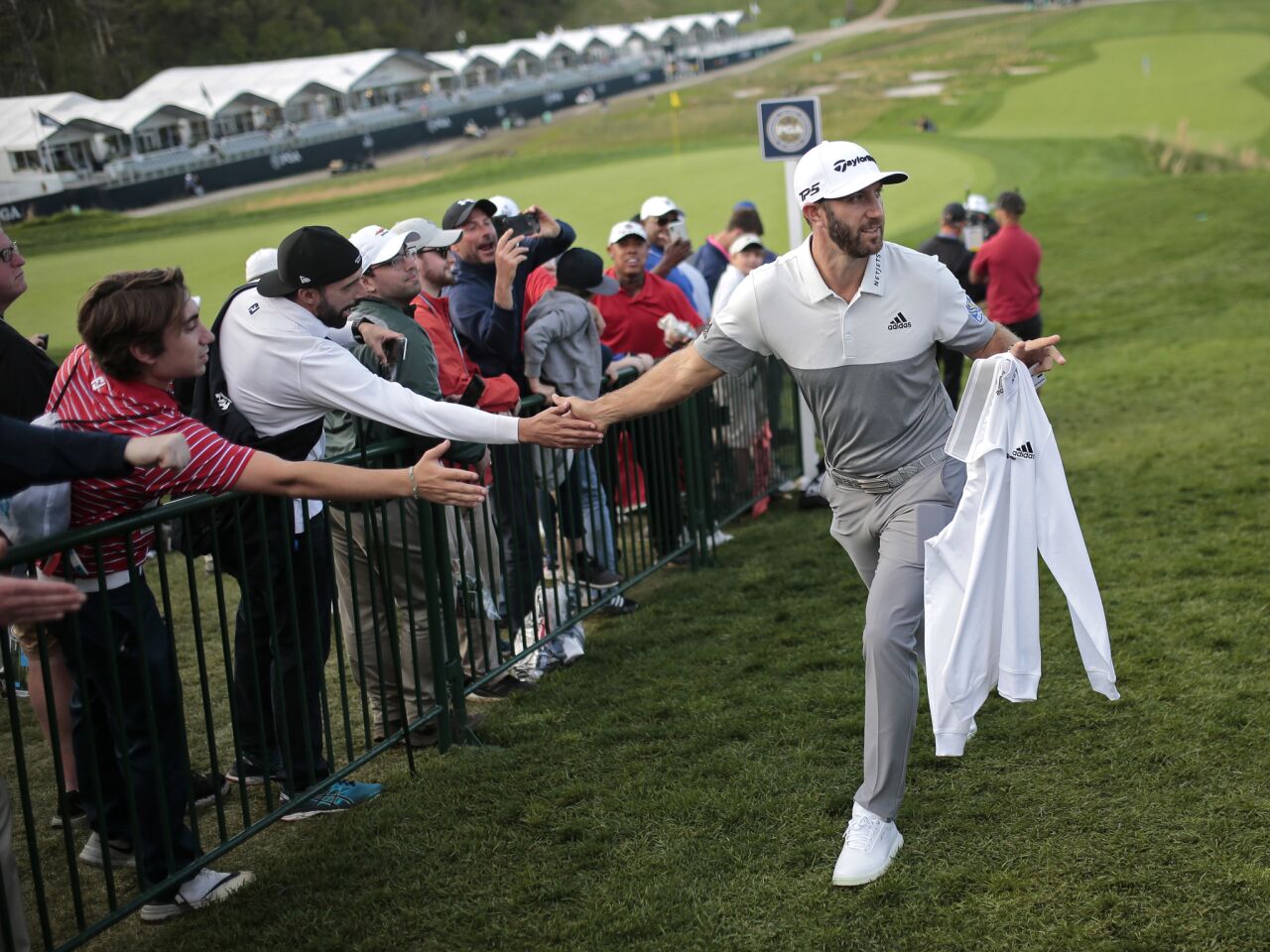 Dustin Johnson greets fans as he walks off the 18th green after finishing the first round of the PGA Championship at Bethpage Black in Farmingdale, N.Y.