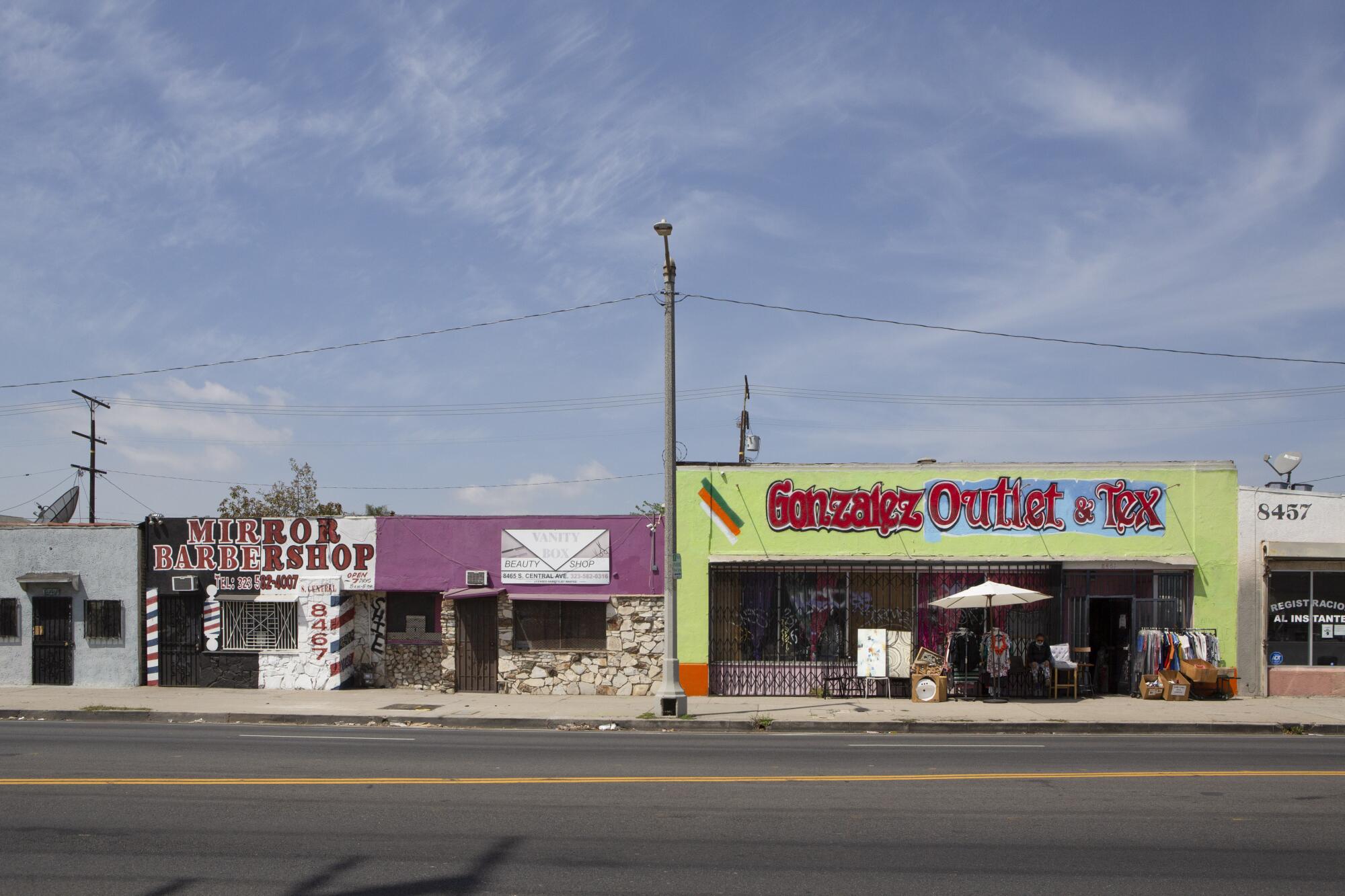 Storefronts on an empty street include Mirror Barbershop and Gonzalez Outlet
