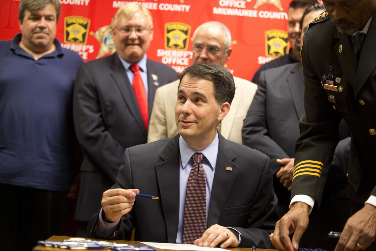 Wisconsin Gov. Scott Walker signs a bill Wednesday in Milwaukee that eliminates a 48-hour waiting period for handgun purchases.