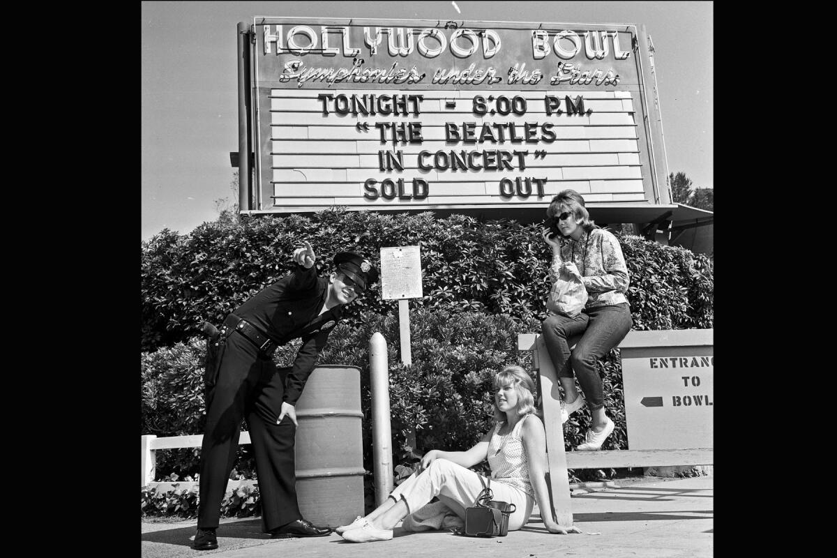 Officer Robert Yocum tells Beatles fans Chelie Mylott, center, and Melody Yapscott to move from their spot in front of the Hollywood Bowl on Aug. 23, 1964. They had no tickets but hoped to get them from scalpers or sneak in. This photo ran in the next day's Times.