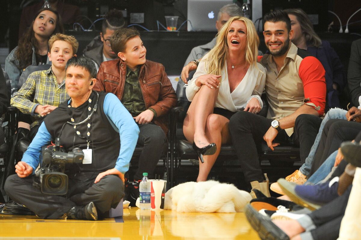 Two teen boys sit with their mom and her boyfriend at a basketball game