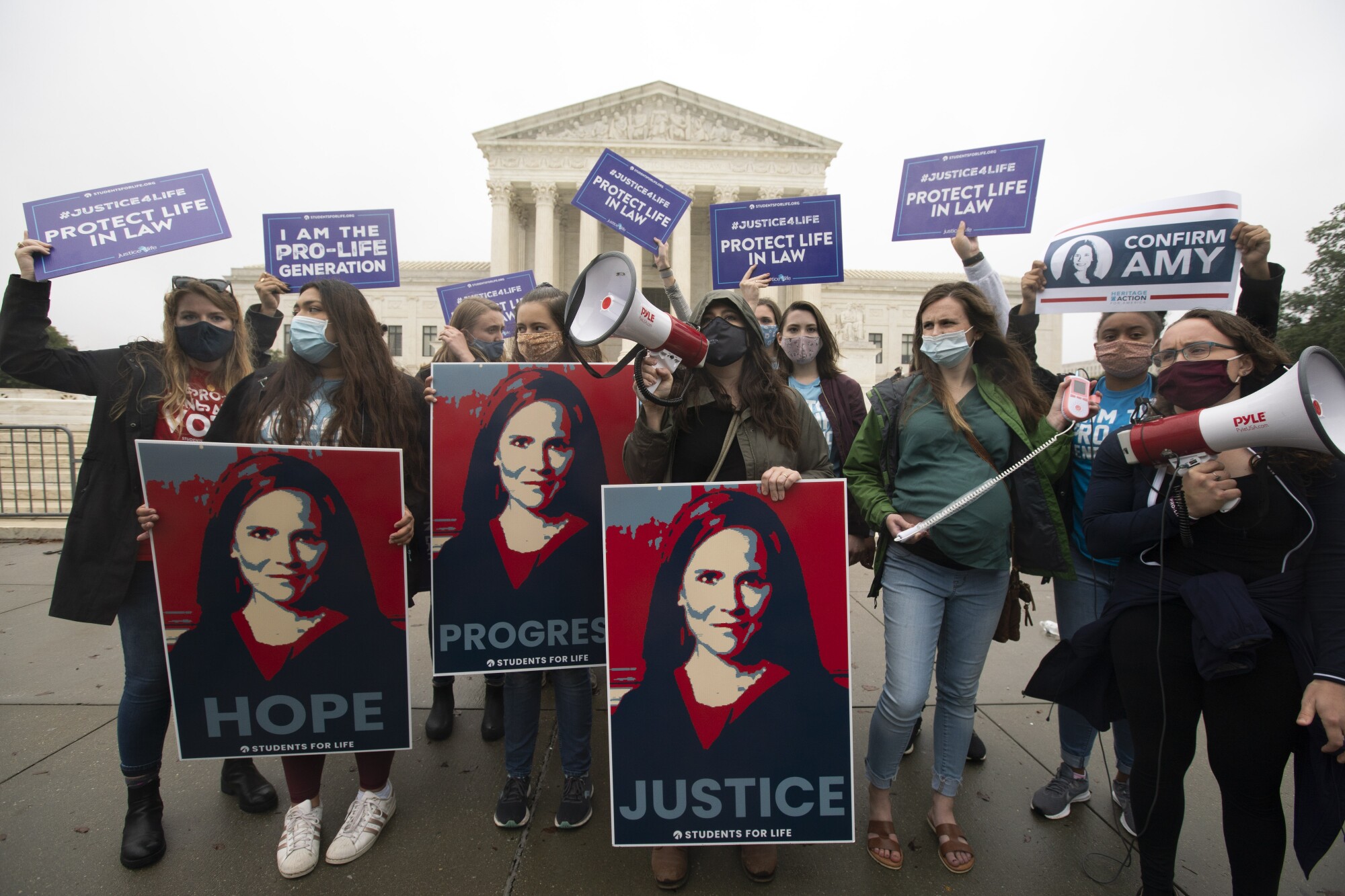 Amy Coney Barrett carry "pro-life" signs and posters with her likeness outside the Supreme Court.