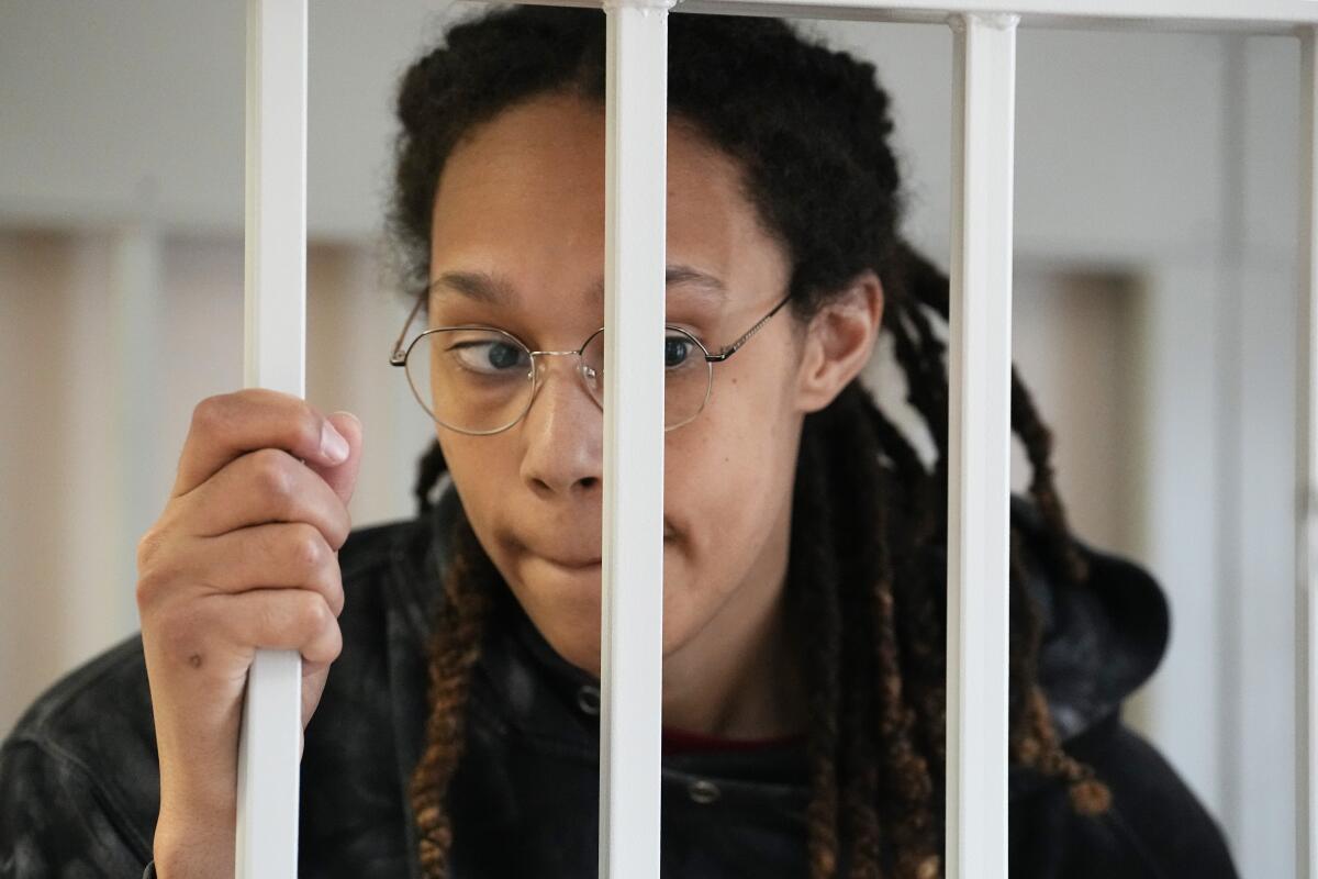 WNBA star Brittney Griner stands in a cage at a court room.