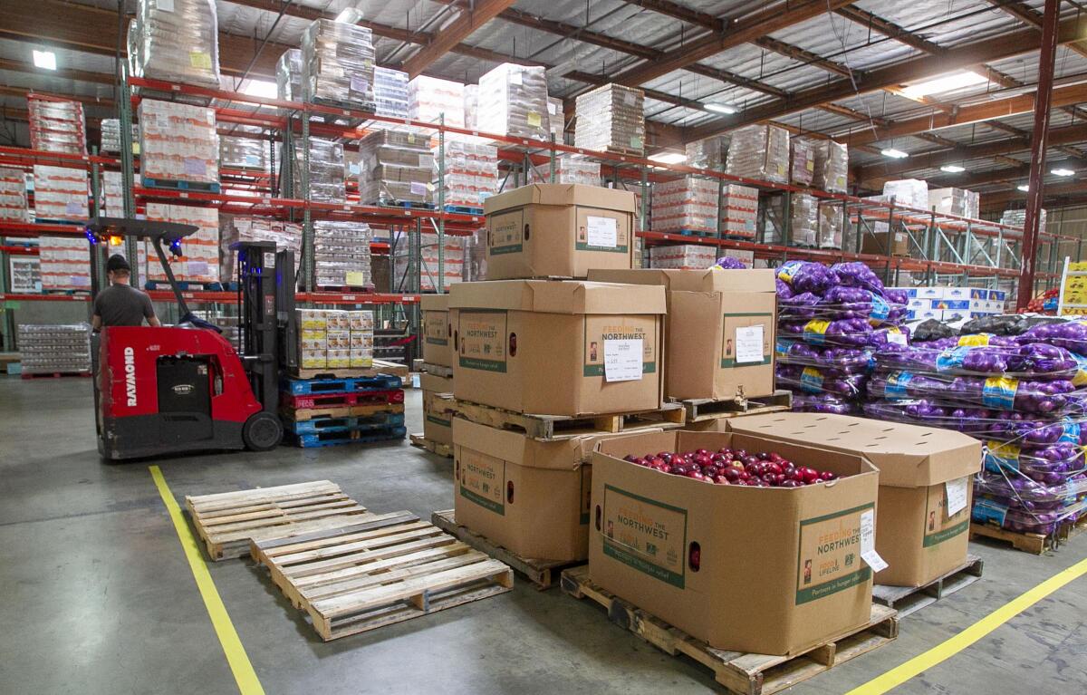A warehouse containing large bins and bags of onions and a forklift operator lifting pallets