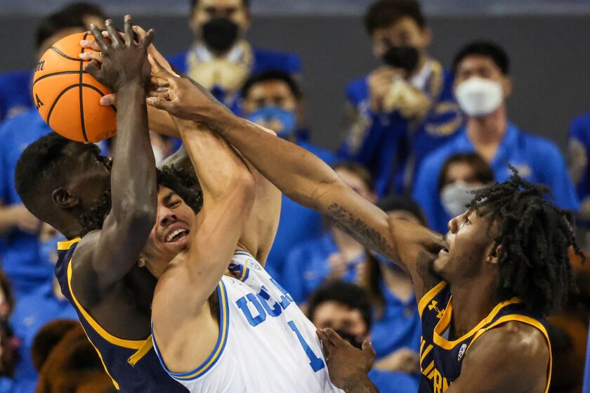 UCLA guard Jules Bernard struggles to control the ball as California's Kuany Kuany and Joel Brown fight for a rebound.