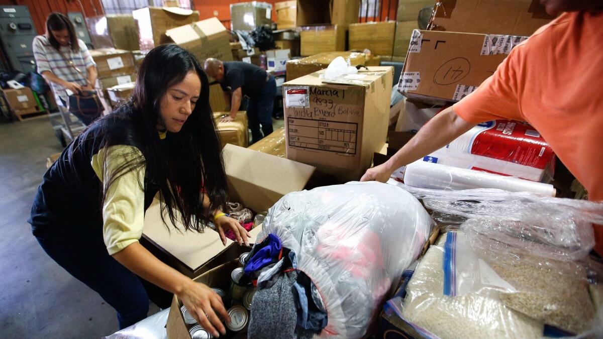 Tere Caicedo, left, packs boxes with donated items at Olarte Transport, a private shipping company in Los Angeles. A total of 16 boxes were filled up with donated necessities, to be shipped to Caicedo's brother, Jose, in Caracas, Venezuela.