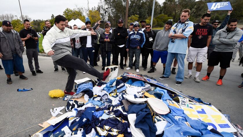 Chris Githens, left, kicks a pile of Chargers memorabilia in front of San Diego Chargers headquarters after the team announced that it will move to Los Angeles Thursday Jan. 12, 2017, in San Diego.