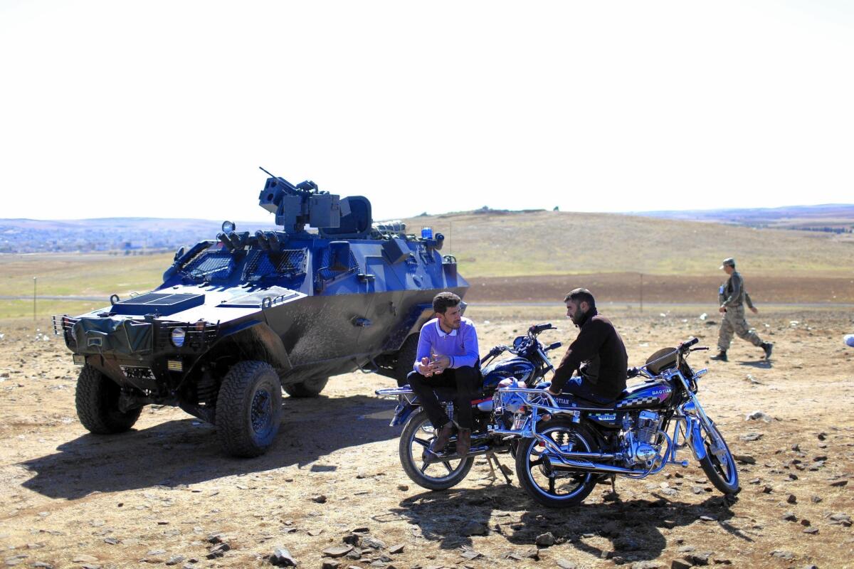 A Turkish army vehicle passes people gathered on the border to watch the battle in Kobani, Syria.