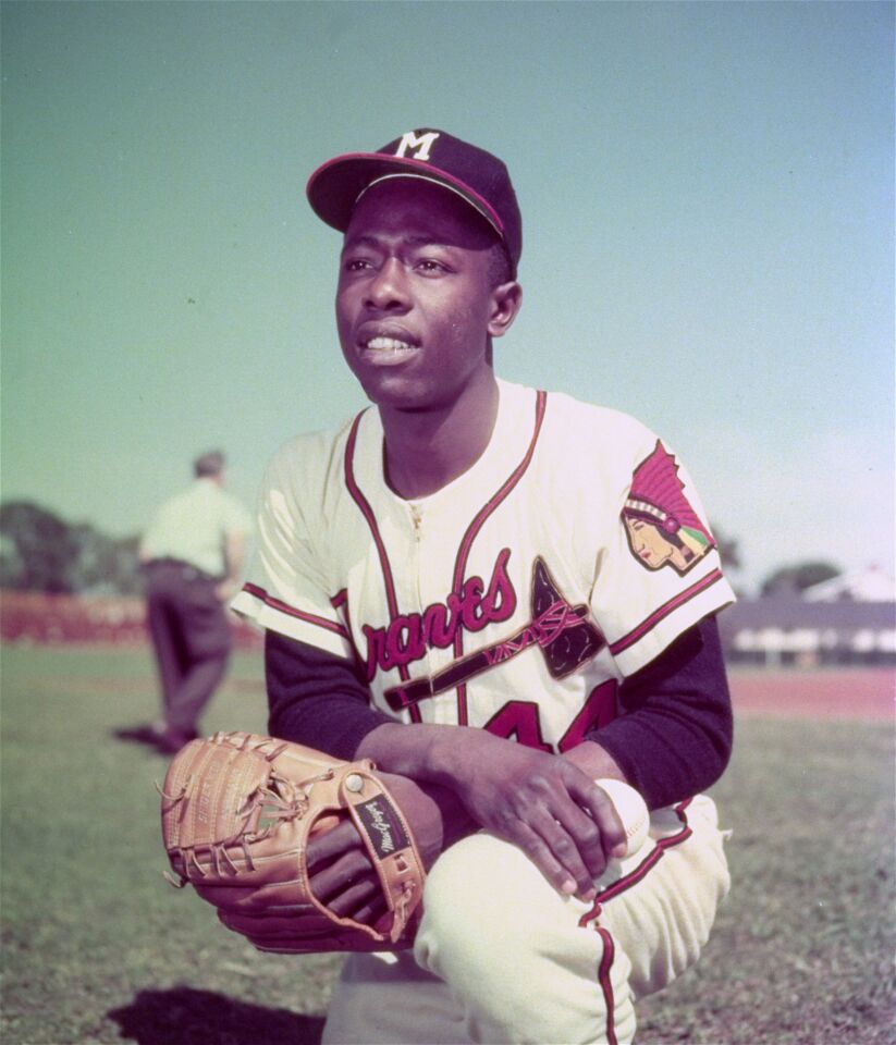 Milwaukee Braves slugger Hank Aaron kneels in the outfield before a game, June 1957