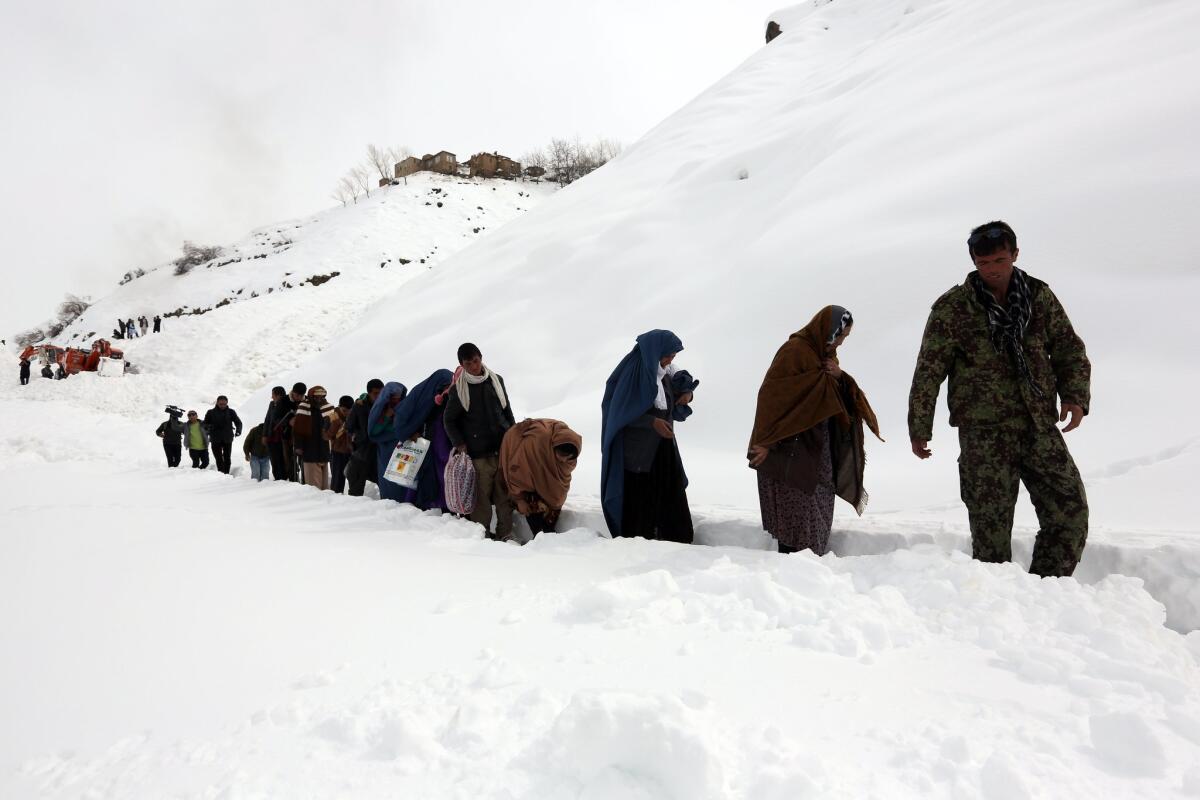 Afghans walk along on a snow-covered road after an avalanche in Abdullah Khil in Panjshir province on March 1