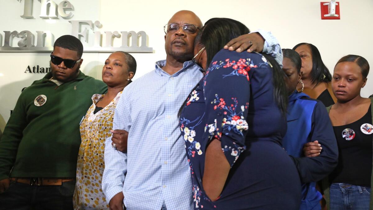 Charles Twyman, third from left, father of Ryan Twyman, comforts daughter Chiquita Twyman as members of Ryan Twyman's family attend a news conference.