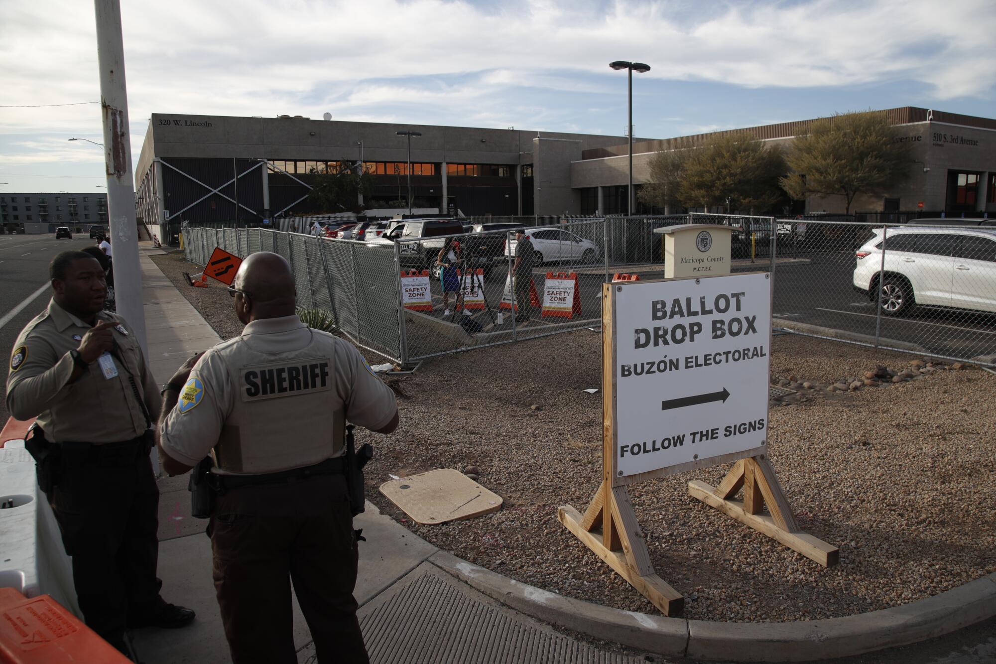 Security guards watch over a ballot drop box 