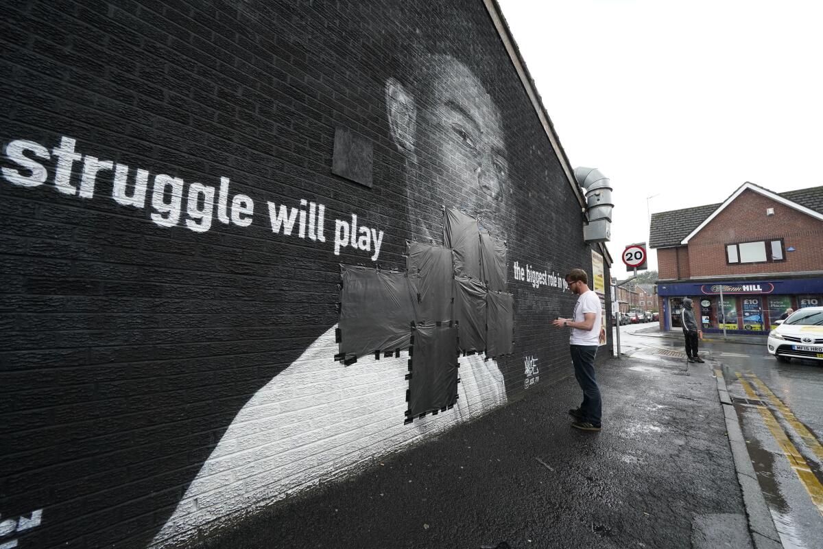 Ed Wellard tapes trash liners across offensive wording on the mural of Marcus Rashford