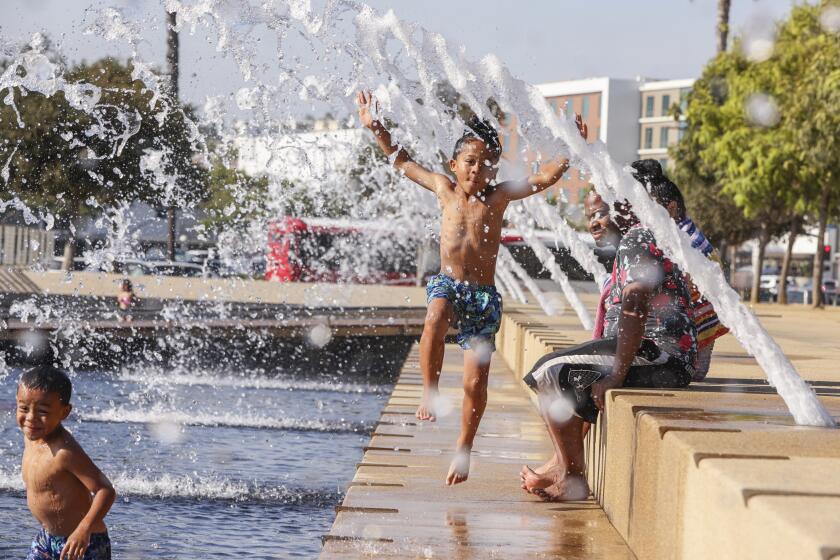 San Diego, CA - September 01: Jeremiah Thomas, 7, jumps and has fun with his family (brother Malakai Thomas (front left), 5) in the fountains at the Waterfront Park on Thursday, Sept. 1, 2022 in San Diego, CA. (Eduardo Contreras / The San Diego Union-Tribune)