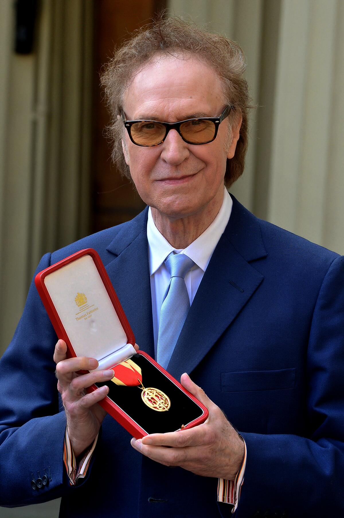 A elderly man holding a medal in a case