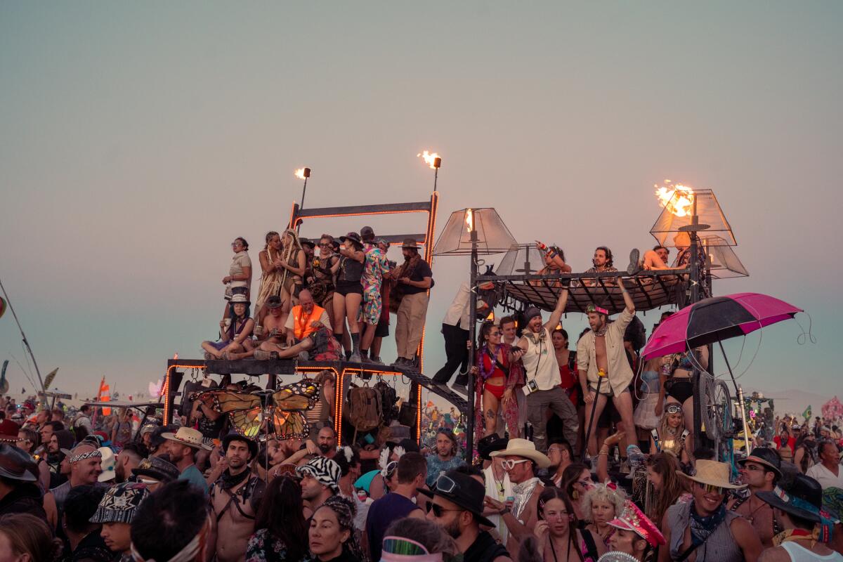 Revelers at Burning Man partying at sunset on one of the many DIY structures on the playa at Black Rock City.