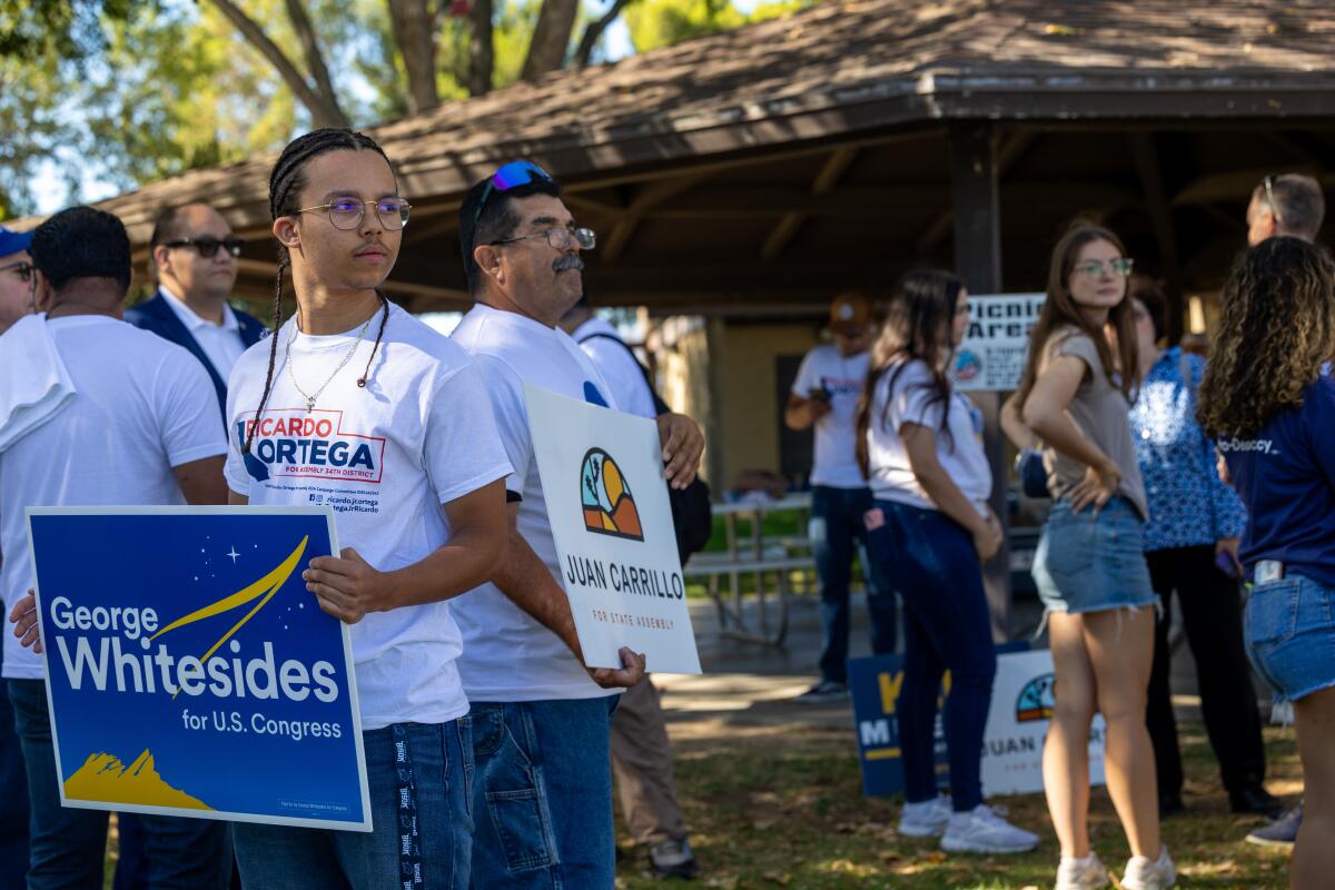 A campaign volunteer holds a sign supporting George Whitesides for U.S. Congress.