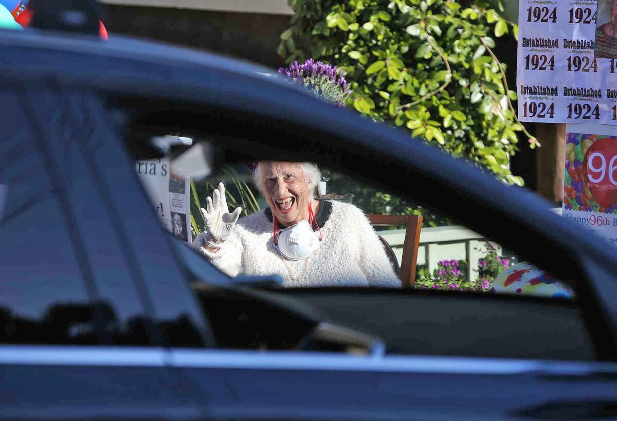 Maria Siani laughs as friends and family members greet her with a drive-by surprise party Wednesday in front of her Laguna Beach home to celebrate her 96th birthday.