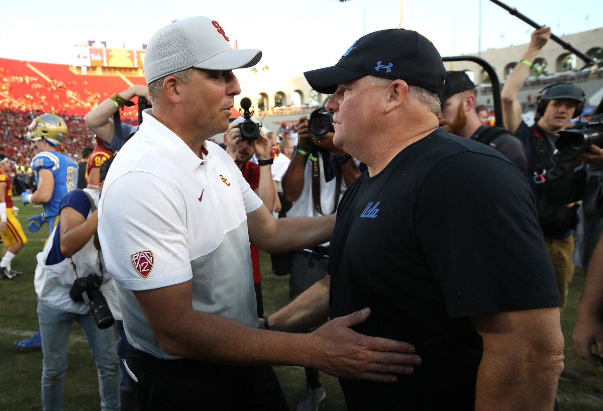USC coach Clay Helton, left, talks with UCLA coach Chip Kelly after a 52-35 Trojans win on Nov. 23, 2019, at the Coliseum.