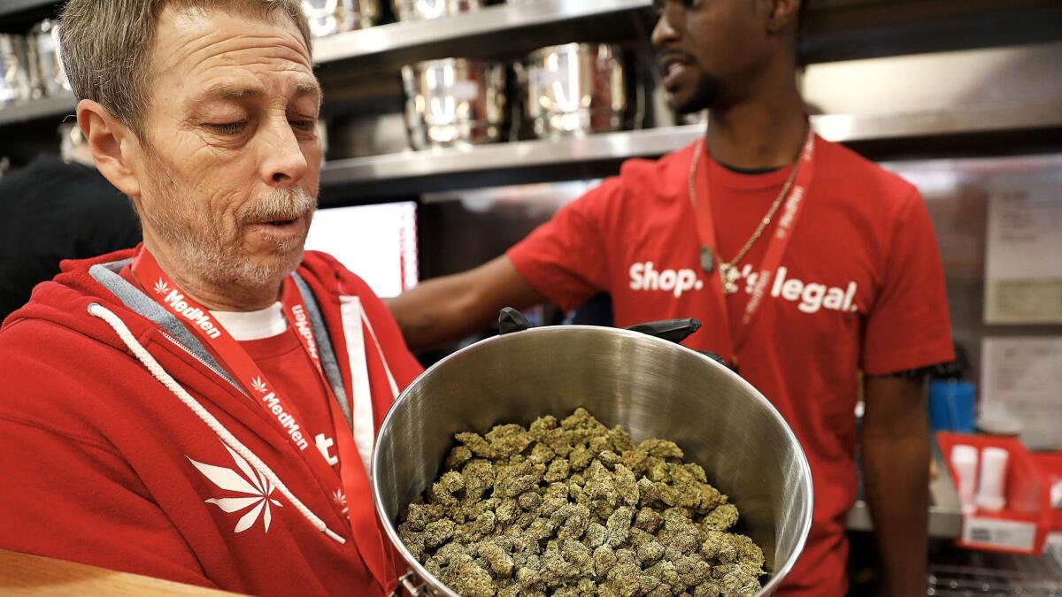 Jeff Cosper shows the inside of a stainless steel pot filled with marijuana for sale at MedMen in West Hollywood.