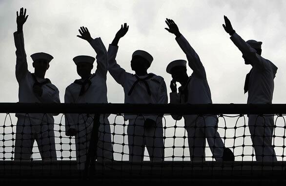 U.S. sailors bid farewell as their ship, the aircraft carrier Kitty Hawk, leaves its port in Yokosuka, Japan, for the last time. The ship is to be decommissioned after nearly half a century of service.