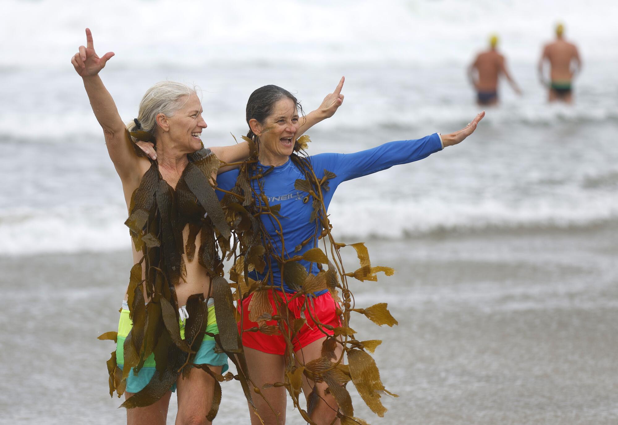 Julie Cairelli and Gretchen Pound return from the ocean wrapped in kelp after going for a dip New Year's Day in La Jolla.