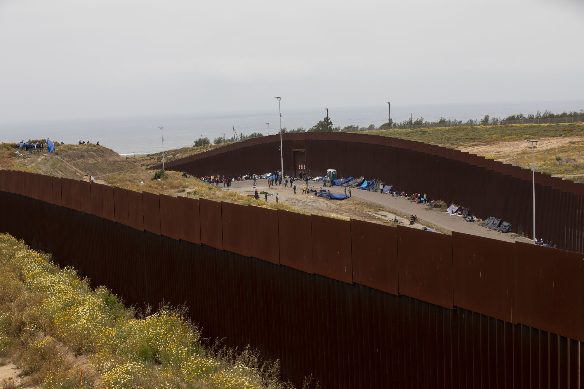 A group of about 500-800 men traveling without their families wait between the border walls  the day after Title 42 ended.