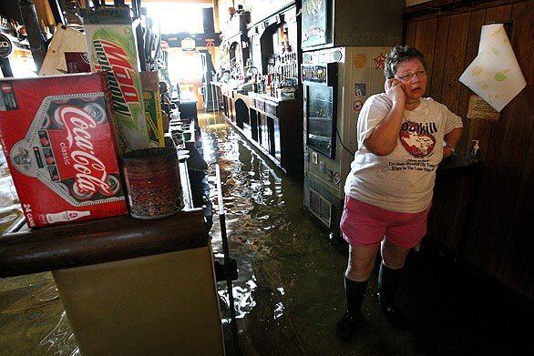 Nancy Jacobs talks on the phone inside her flooded South Side Inn bar in Burlington, Iowa, one of many communities in the Midwest hit by Mississippi River flooding.
