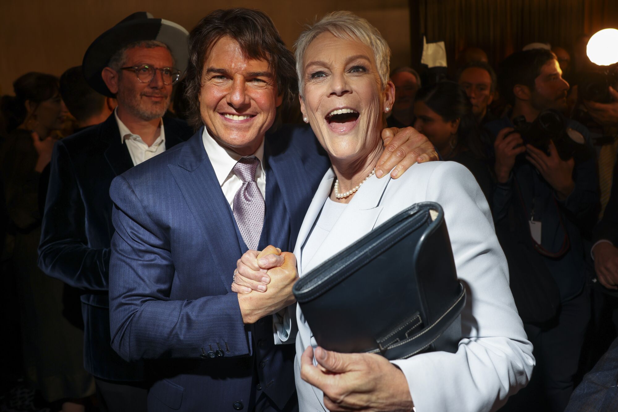 Un homme serre la main d'une femme et pose son autre main sur son épaule. Les deux sourient largement.