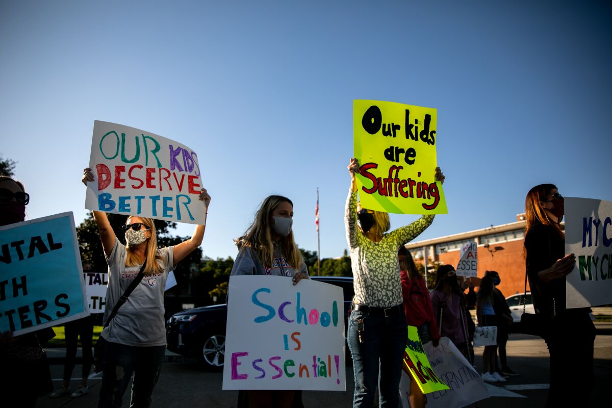 Protesters hold signs at San Diego Unified headquarters in October calling for schools to reopen.
