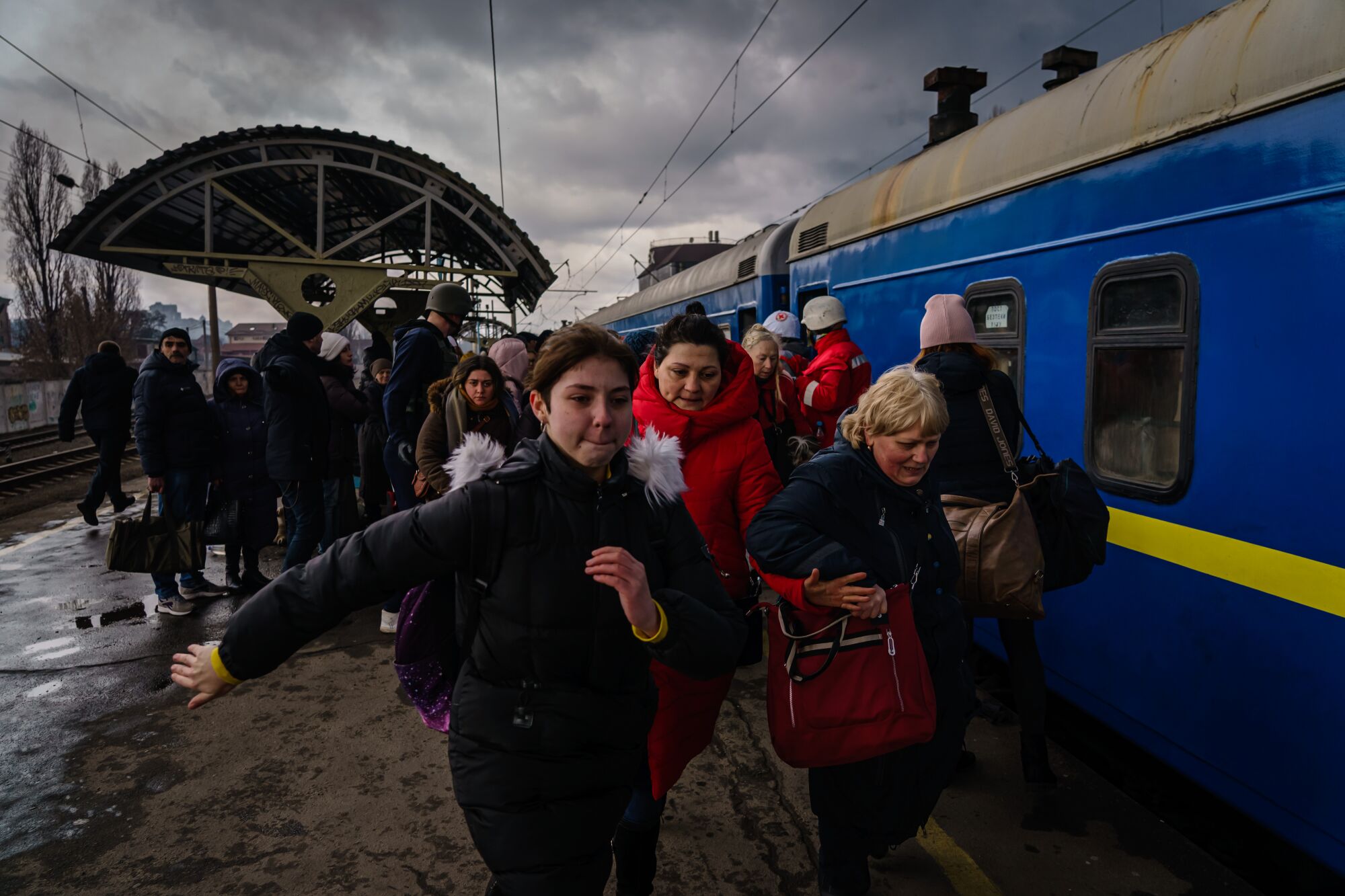 Civilians, mostly women and children, rush to board a train